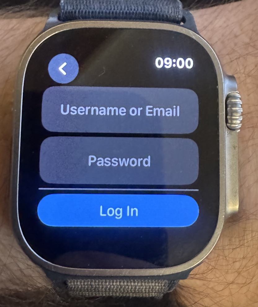 Photo of an Apple Watch Ultra on a wrist showing the Strong app login screen with Username or Email and Password fields and a Log In button